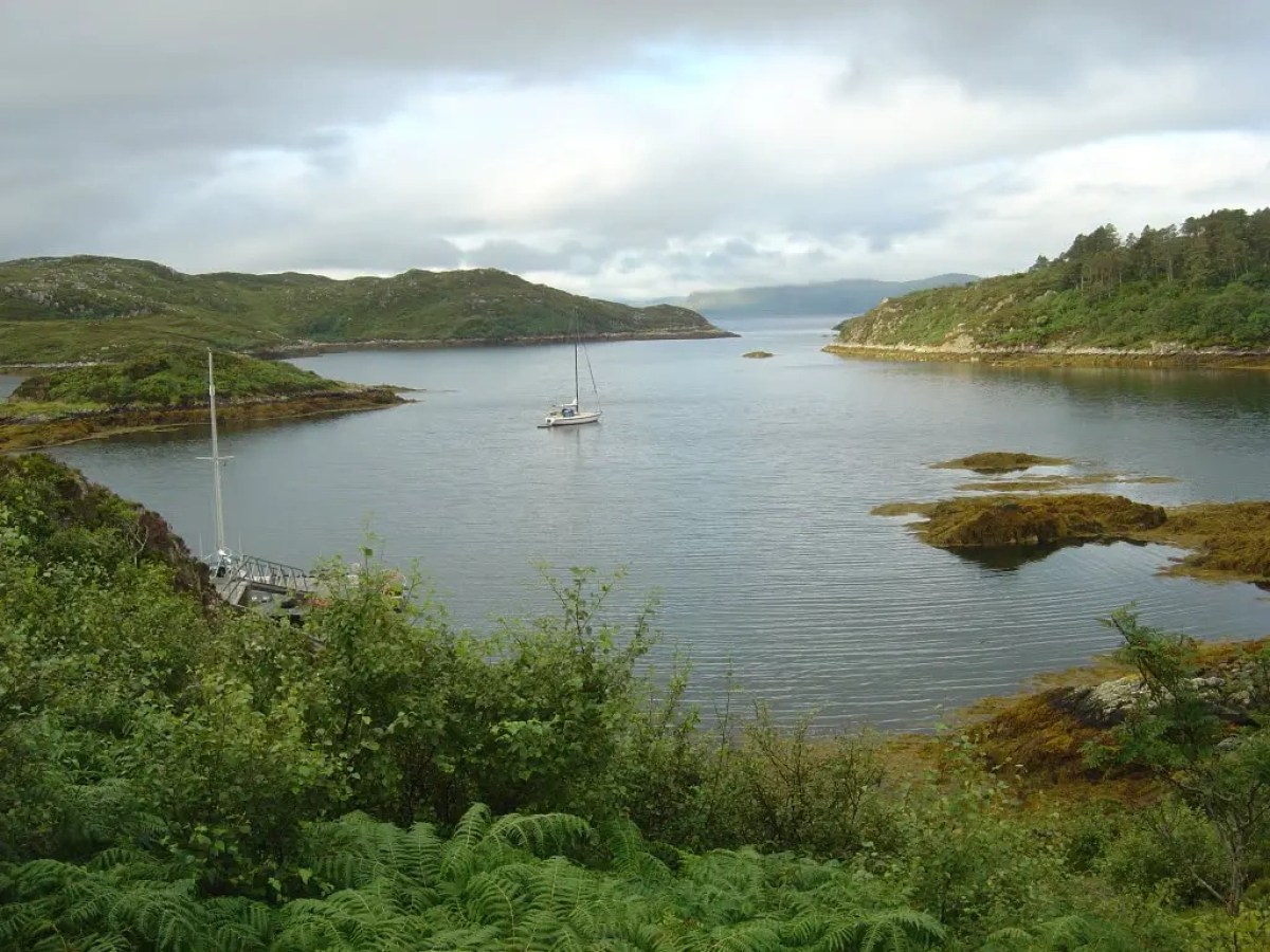 Two boats floating near a rocky coastline with sea caves in the background.