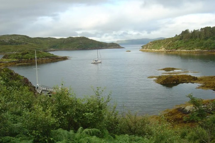 Two boats floating near a rocky coastline with sea caves in the background.