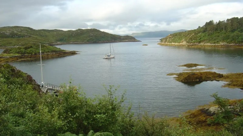 Two boats floating near a rocky coastline with sea caves in the background.