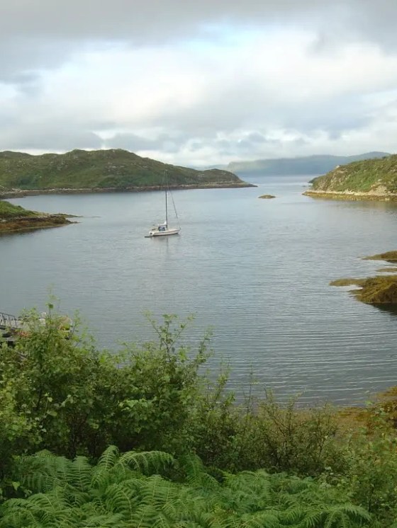 Two boats floating near a rocky coastline with sea caves in the background.